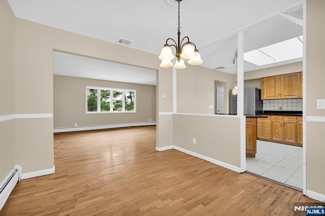 kitchen with stainless steel refrigerator, decorative backsplash, hanging light fixtures, and a baseboard heating unit