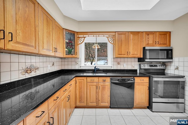 kitchen featuring tasteful backsplash, sink, dark stone counters, light tile patterned floors, and stainless steel appliances