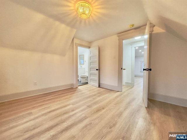 additional living space featuring vaulted ceiling and light wood-type flooring