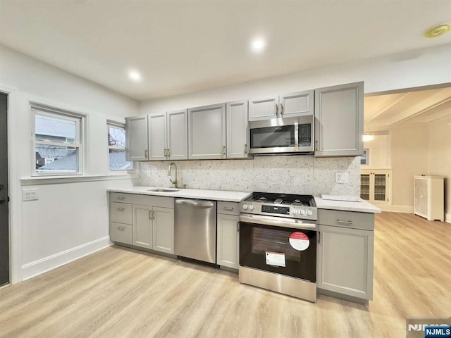 kitchen with decorative backsplash, gray cabinets, and appliances with stainless steel finishes