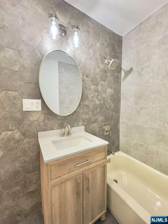 bathroom featuring vanity, tub / shower combination, and tile walls