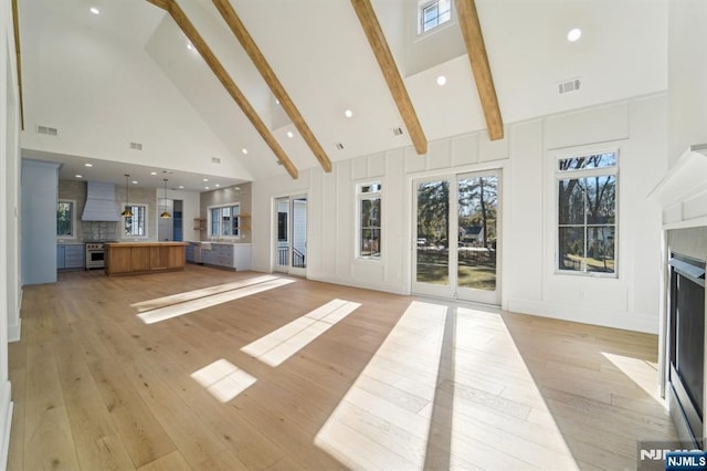 unfurnished living room featuring beamed ceiling, high vaulted ceiling, and light wood-type flooring