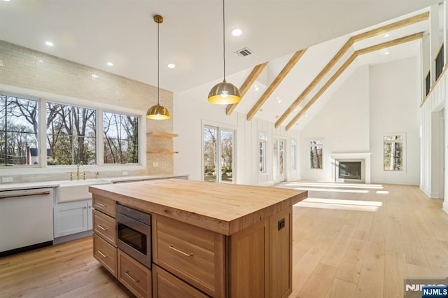 kitchen with wood counters, sink, decorative light fixtures, stainless steel microwave, and white dishwasher