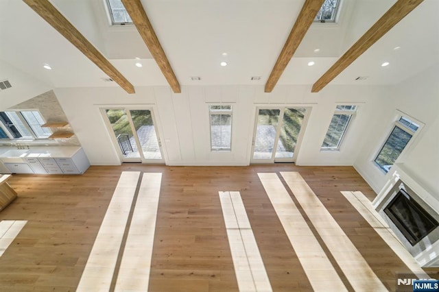 unfurnished living room featuring beamed ceiling and wood-type flooring