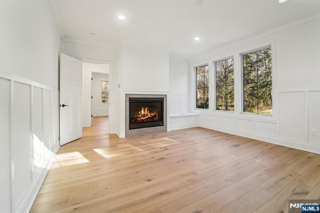 unfurnished living room with ornamental molding and light wood-type flooring