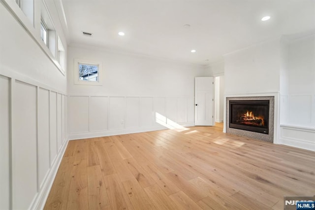 unfurnished living room featuring ornamental molding, a tile fireplace, and light wood-type flooring