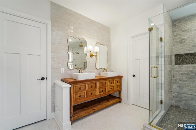 bathroom featuring a shower with door and vanity