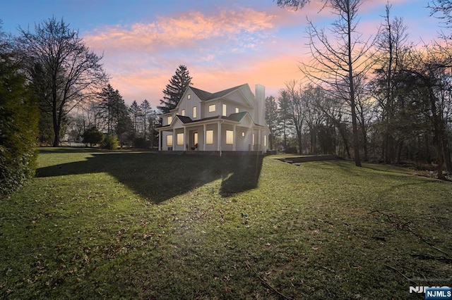 property exterior at dusk featuring a lawn