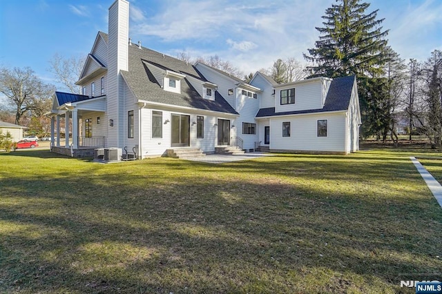 rear view of house featuring central AC unit and a lawn