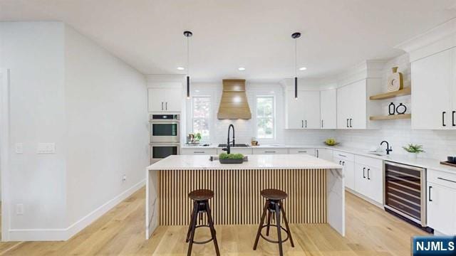 kitchen with stainless steel double oven, beverage cooler, a kitchen breakfast bar, a center island, and open shelves