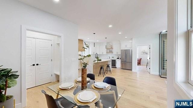 dining room featuring recessed lighting, light wood finished floors, and wine cooler