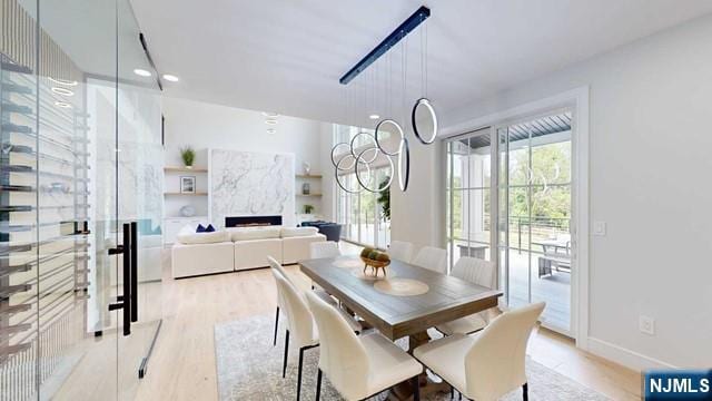 dining area with light wood-type flooring, a fireplace, and baseboards