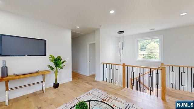 corridor featuring baseboards, wood finished floors, an upstairs landing, and recessed lighting