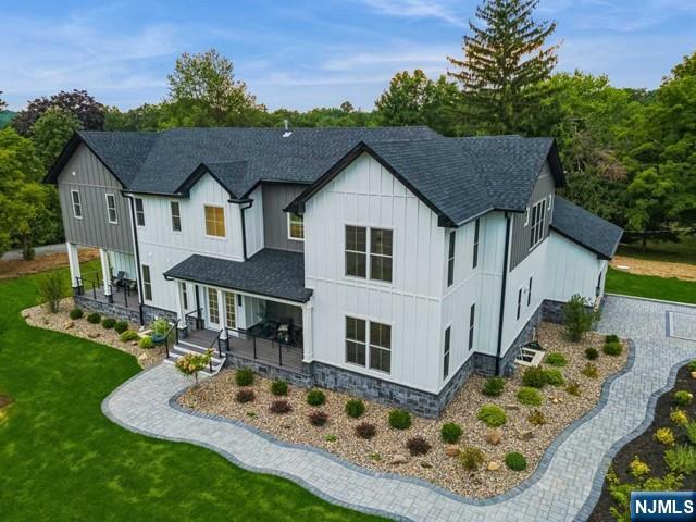 back of property featuring a yard, a porch, board and batten siding, and roof with shingles