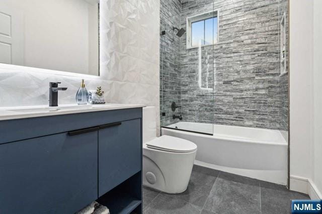 full bathroom featuring shower / tub combination, toilet, tile walls, vanity, and tile patterned floors