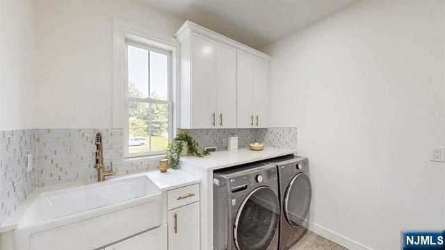 laundry room featuring baseboards, cabinet space, independent washer and dryer, and a sink