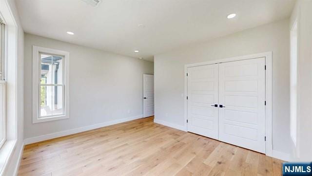 unfurnished bedroom featuring a closet, recessed lighting, light wood-style flooring, and baseboards