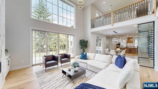 living room featuring a towering ceiling, baseboards, wood finished floors, and recessed lighting