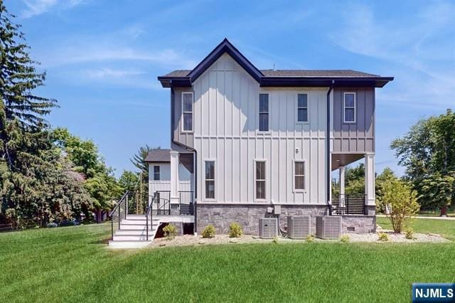 back of house featuring a yard, central AC unit, and board and batten siding