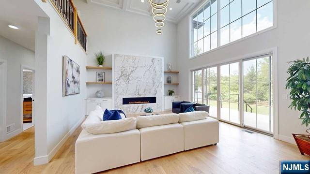 living room featuring light wood-style floors, a premium fireplace, and baseboards