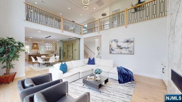 living room featuring recessed lighting, a high ceiling, wood finished floors, visible vents, and baseboards