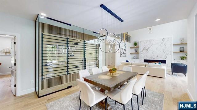 dining area featuring a fireplace, a notable chandelier, light wood finished floors, recessed lighting, and baseboards