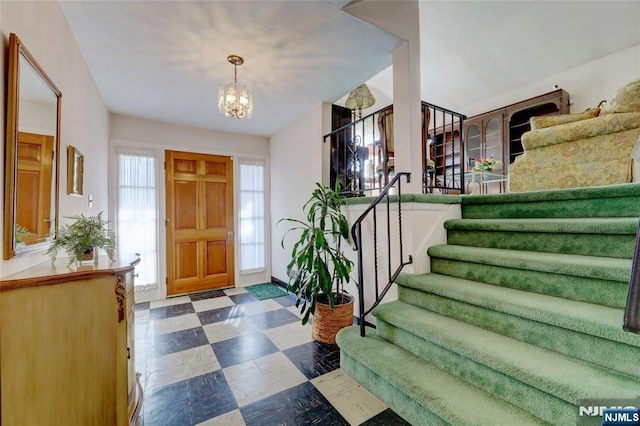 foyer entrance featuring stairs, a notable chandelier, and tile patterned floors