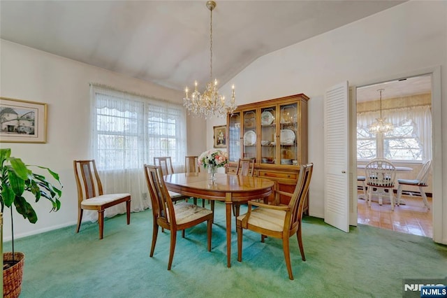 dining space featuring carpet floors, a notable chandelier, and lofted ceiling