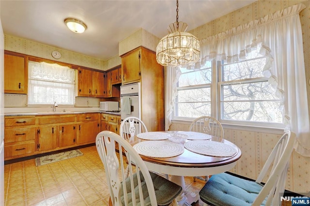 dining area featuring wallpapered walls, a notable chandelier, and light floors