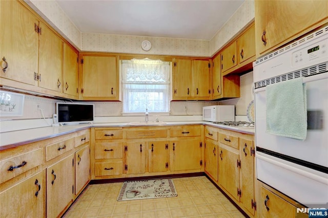 kitchen with a warming drawer, light floors, light countertops, a sink, and white appliances