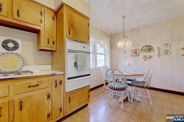 kitchen featuring wallpapered walls, baseboards, oven, light countertops, and a warming drawer