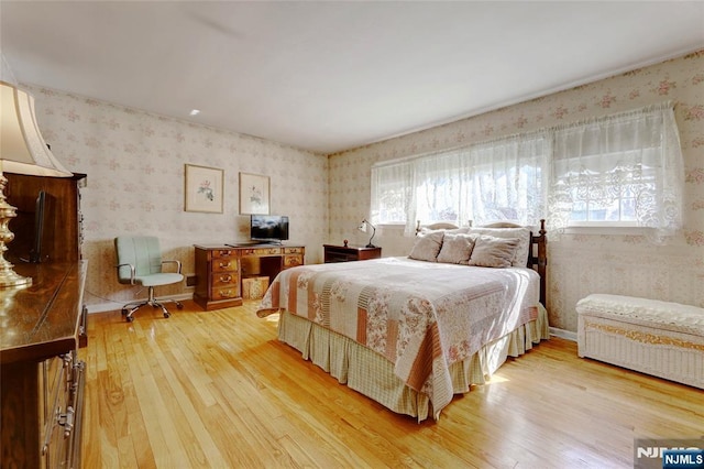 bedroom with wood finished floors, multiple windows, and wallpapered walls