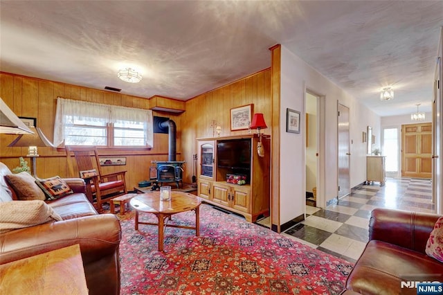 living area with a wood stove, wood walls, a healthy amount of sunlight, and tile patterned floors