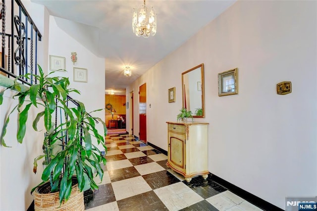 hallway featuring baseboards, light floors, and an inviting chandelier