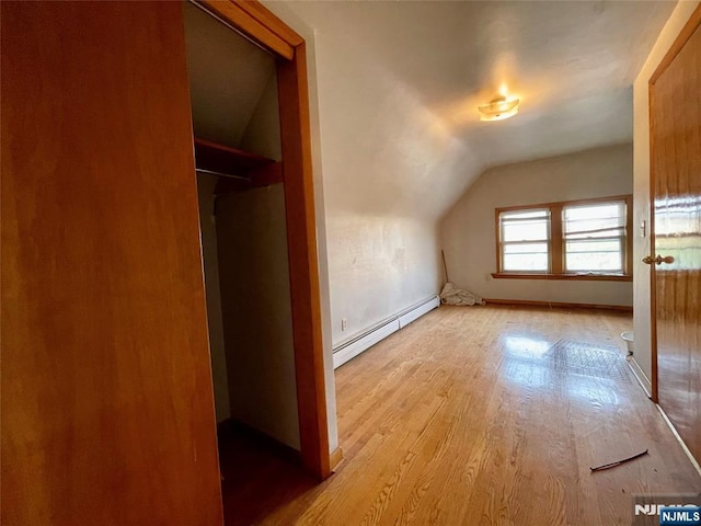 additional living space featuring vaulted ceiling, a baseboard heating unit, and light hardwood / wood-style flooring