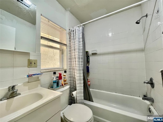 full bathroom featuring tile walls, decorative backsplash, vanity, toilet, and shower / bath combo