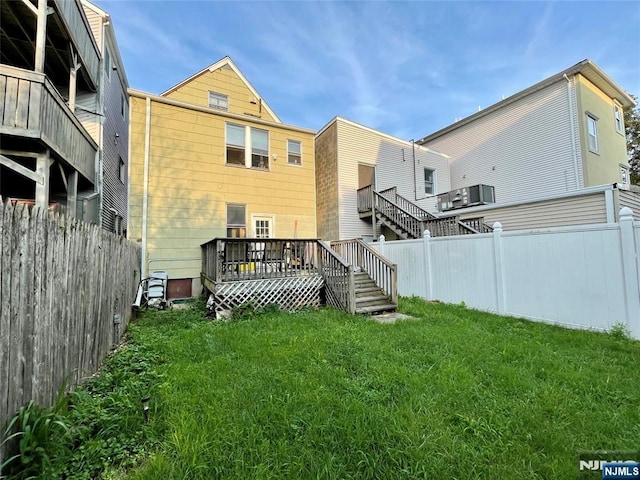 back of house with a deck and a lawn