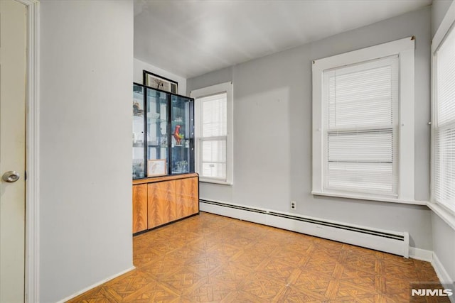 empty room with light parquet flooring and a baseboard heating unit