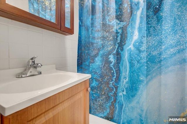 bathroom with vanity, backsplash, and tile walls