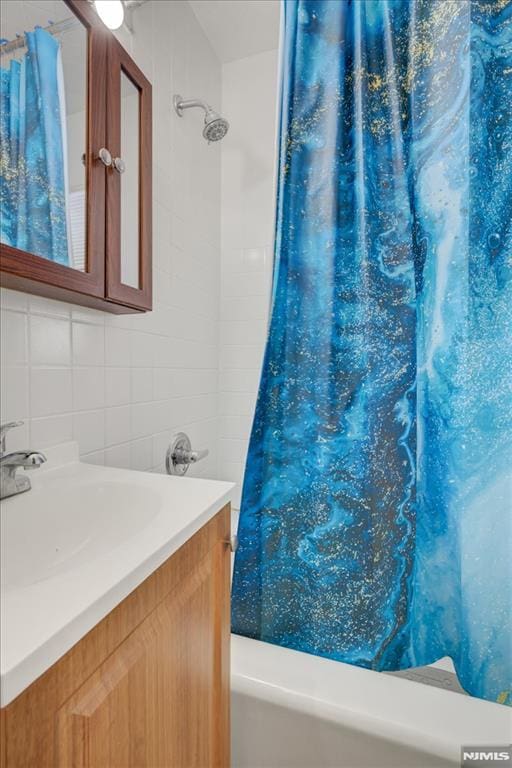 bathroom featuring tasteful backsplash, vanity, tile walls, and shower / bathtub combination with curtain