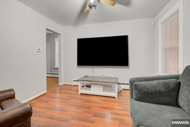 living room with wood-type flooring, ceiling fan, and baseboard heating