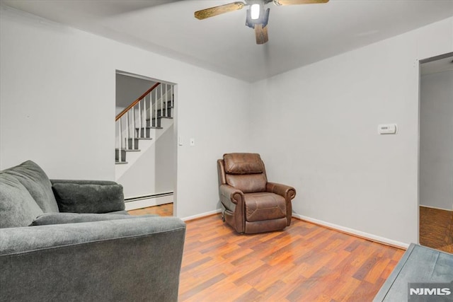 sitting room featuring wood-type flooring, a baseboard heating unit, and ceiling fan