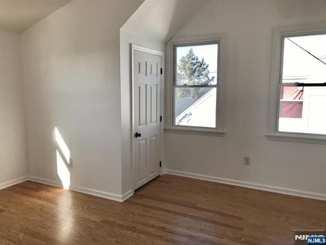 unfurnished room with dark hardwood / wood-style floors and vaulted ceiling