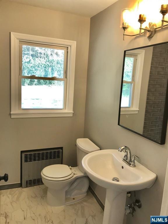 bathroom featuring sink, a wealth of natural light, radiator heating unit, and toilet