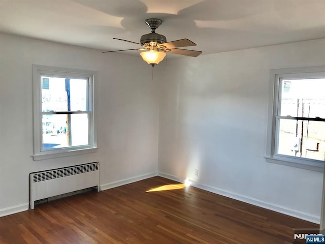 unfurnished room with radiator heating unit, dark hardwood / wood-style floors, and ceiling fan