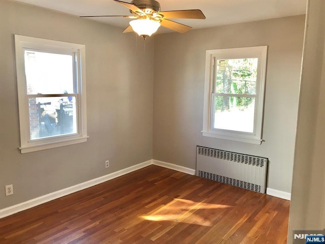 unfurnished room featuring ceiling fan, radiator heating unit, and dark hardwood / wood-style flooring