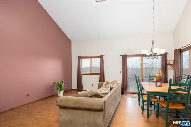 living room with high vaulted ceiling, a notable chandelier, and light hardwood / wood-style floors