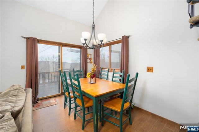 dining area with wood-type flooring, a notable chandelier, and high vaulted ceiling