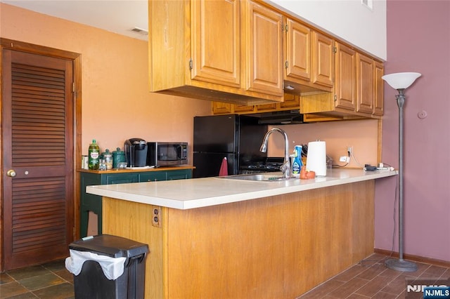 kitchen featuring black refrigerator, kitchen peninsula, and sink