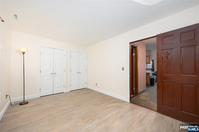 bedroom featuring multiple closets and light wood-type flooring